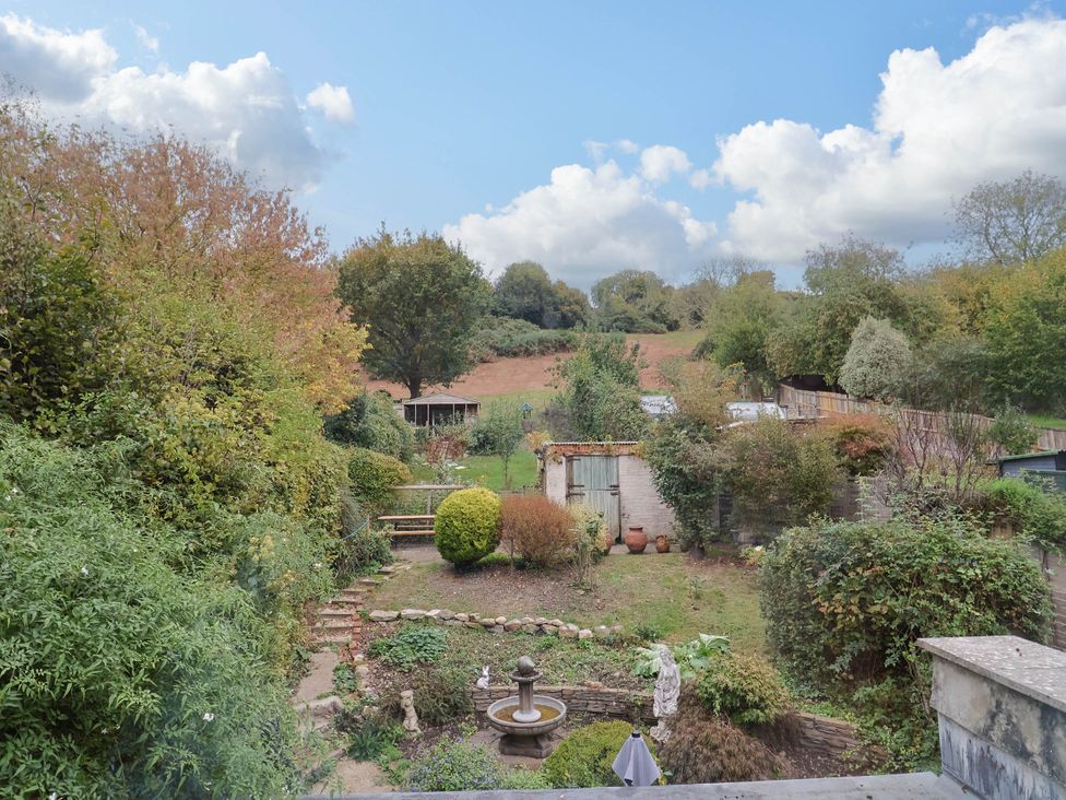 A garden with a fountain and greenery at Coombe Cottage Apartment in Axmouth