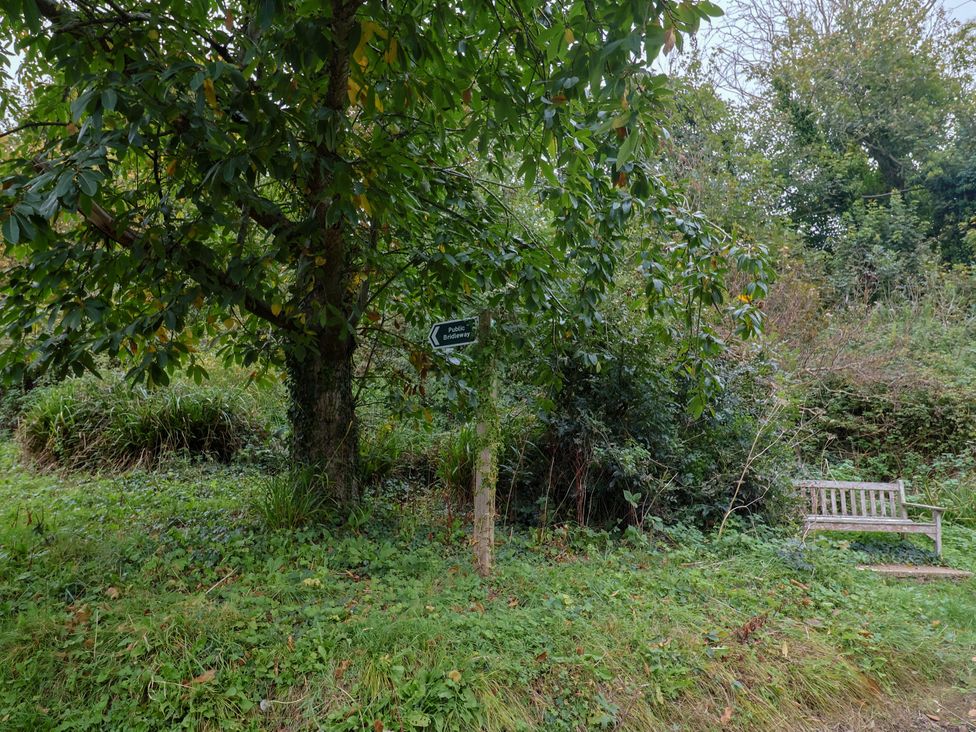 A public footpath sign near a bench and tree at Coombe Cottage Apartment Axmouth