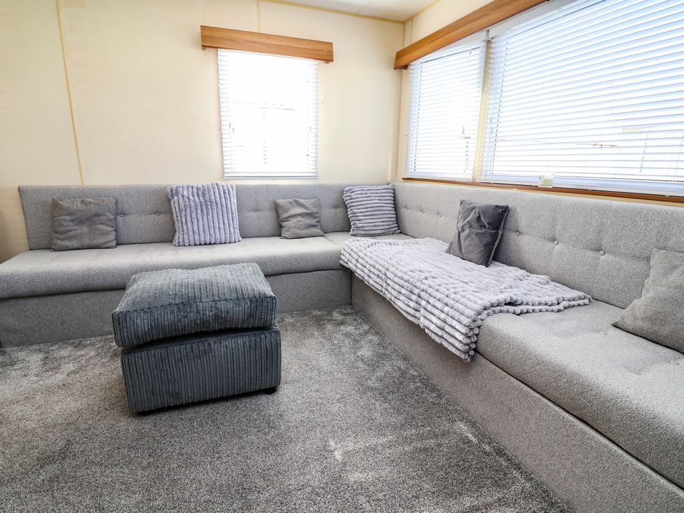 A living room with a sectional sofa and ottoman at Beach Fields 45 in Kinmel Bay