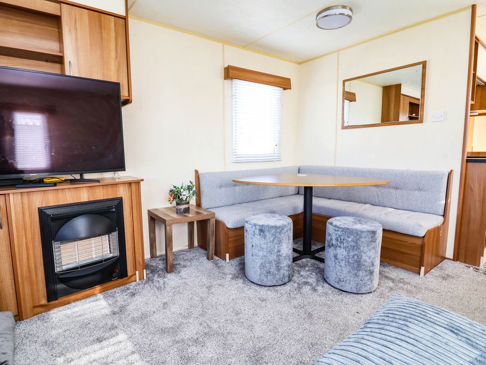 A living room with a television and bench seating at Beach Fields 45 in Kinmel Bay