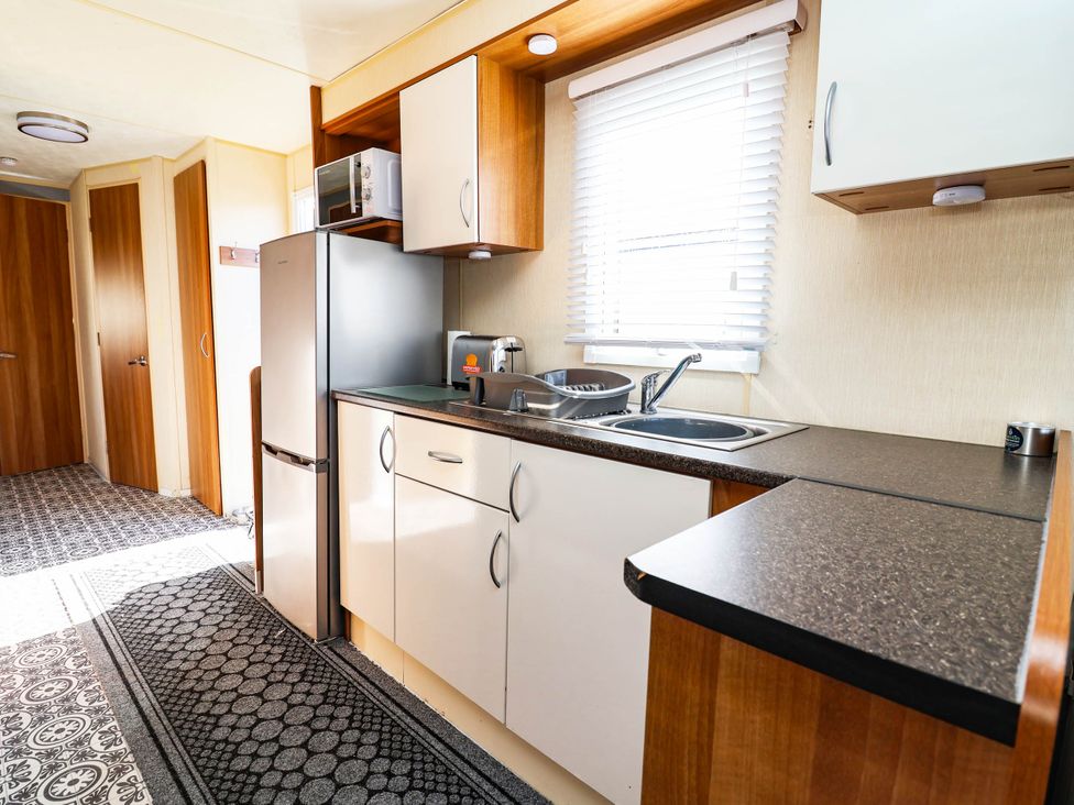 A kitchen with refrigerator, sink, and microwave at Beach Fields 45 Kinmel Bay