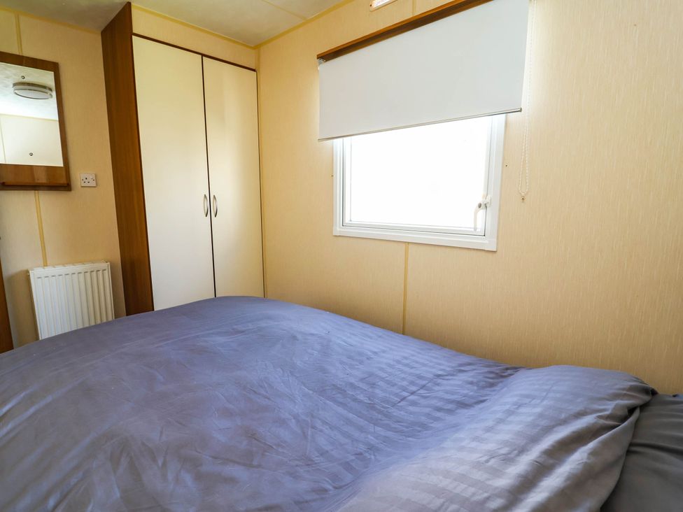 A bedroom with a bed and wardrobe at Beach Fields 45 in Kinmel Bay