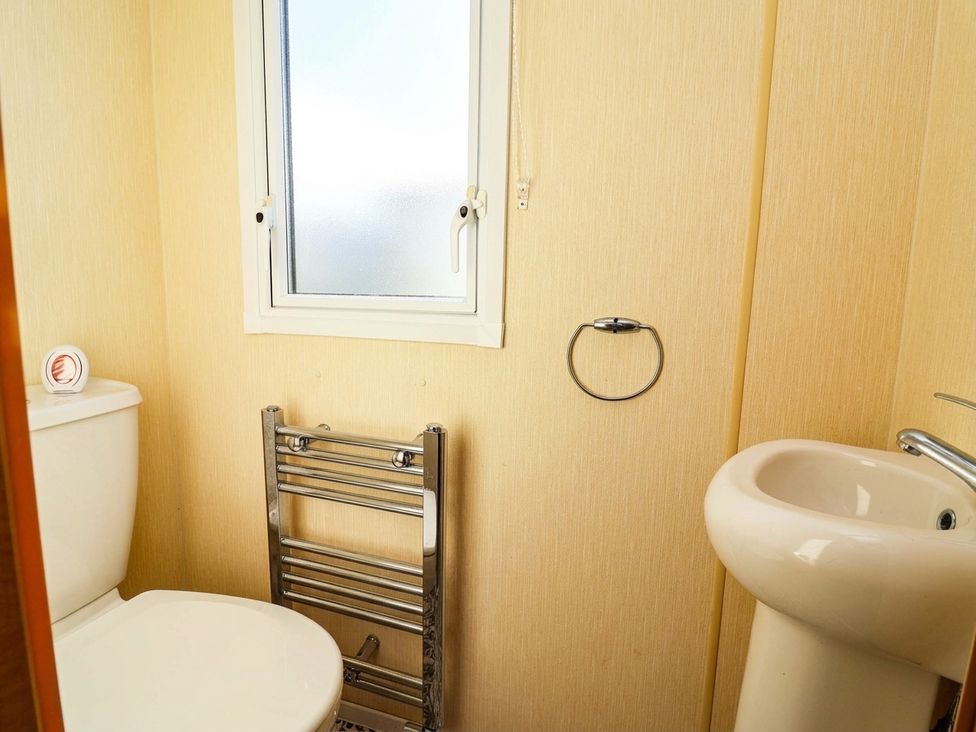 A bathroom with a toilet, washbasin, and window at Beach Fields 45 Kinmel Bay