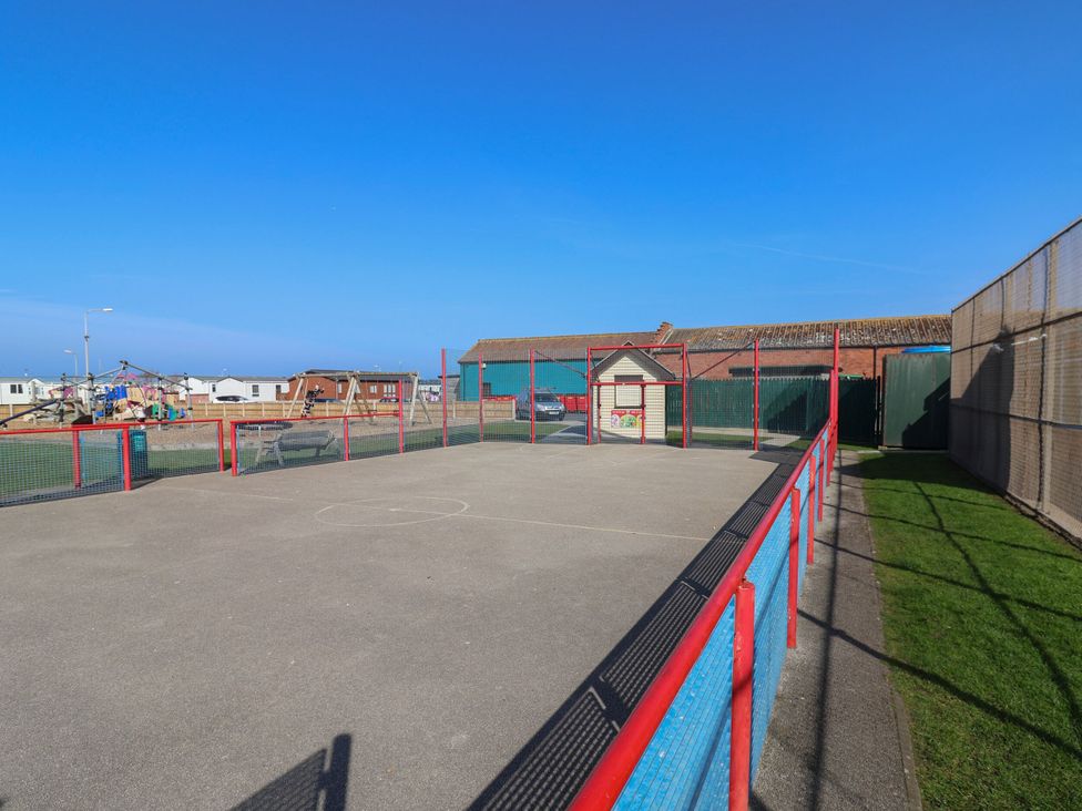 A playground with a fenced area and buildings at Beach Fields 45 Kinmel Bay