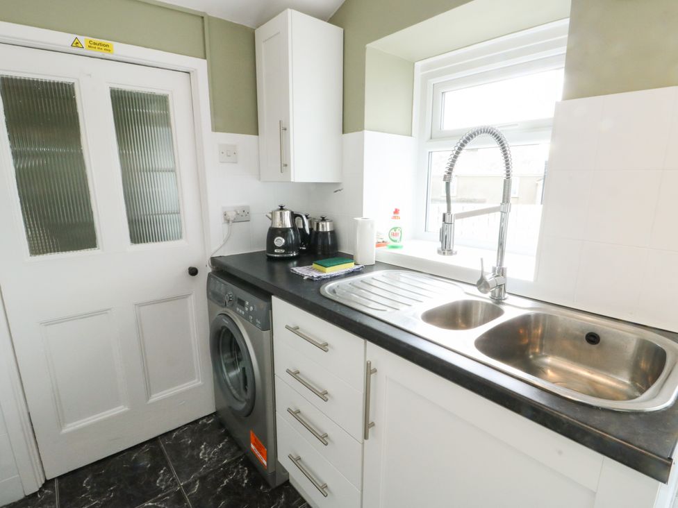 A kitchen with a washing machine and sink at Mor Awelon in Moelfre