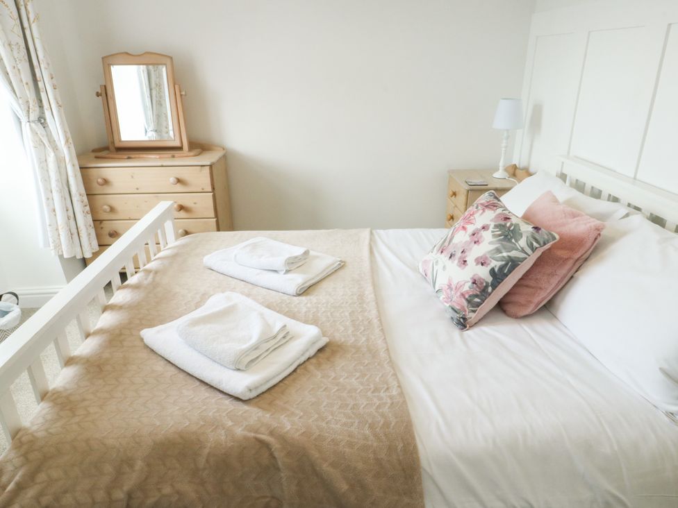 A bedroom with a bed, pillows, and a mirror at Mor Awelon in Moelfre