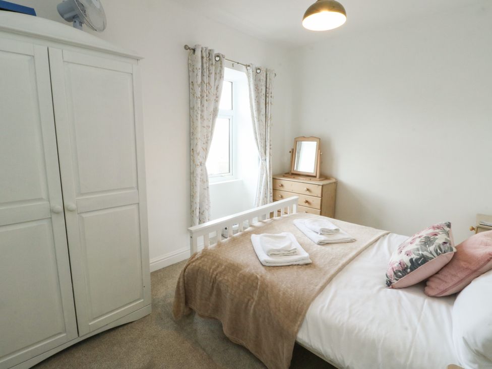 A bedroom with a bed, wardrobe, and window at Mor Awelon in Moelfre