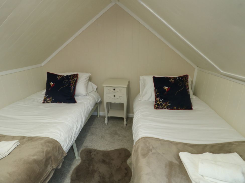 A bedroom with two beds and a nightstand at Mor Awelon in Moelfre