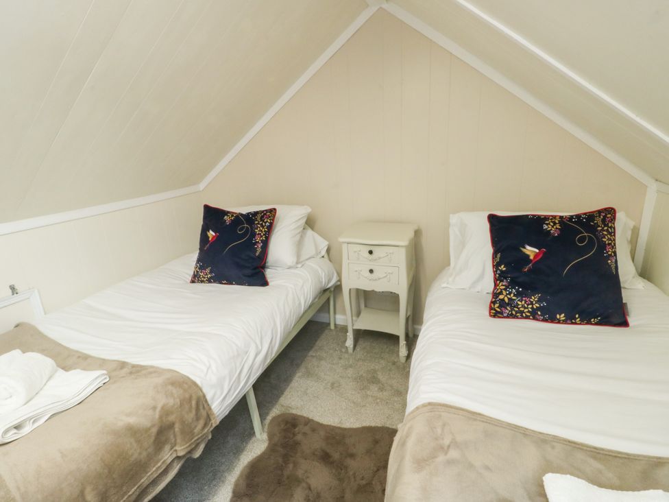 A bedroom with two beds and a nightstand at Mor Awelon in Moelfre