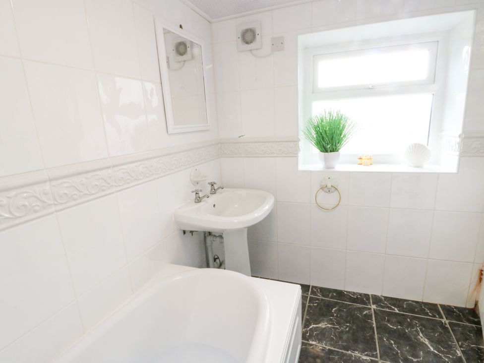 A bathroom with a bathtub and sink at Mor Awelon in Moelfre