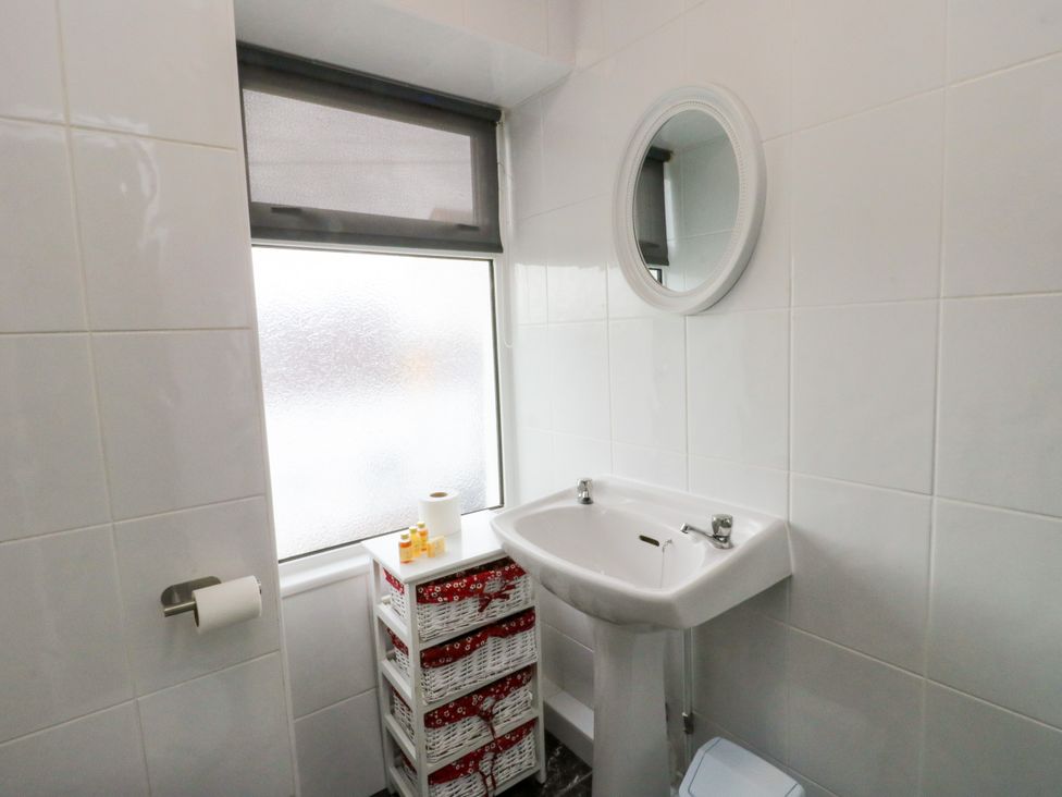 A bathroom with a sink and storage basket at Mor Awelon in Moelfre
