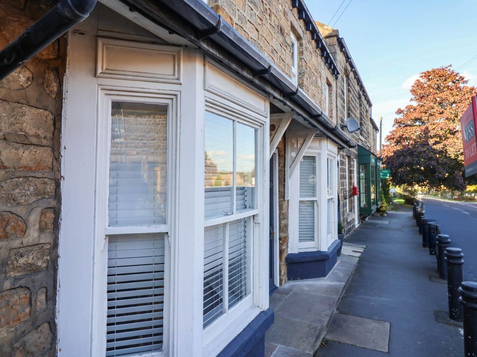 A street view of residential buildings with stone walls and windows at Winksey Cottage in Harrogate