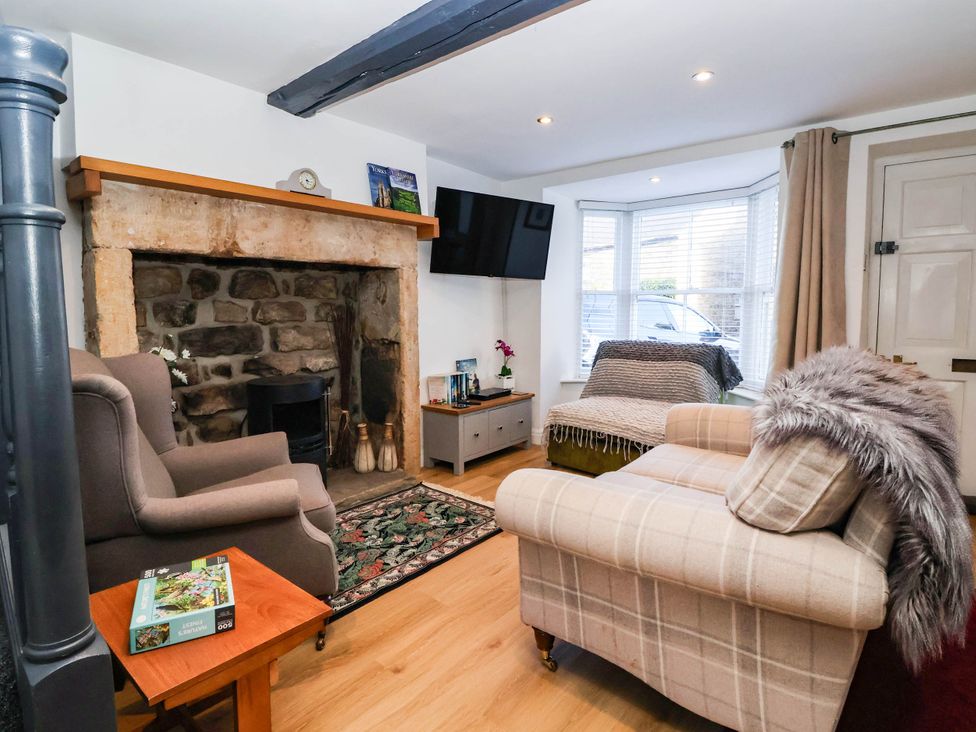 A living room with a fireplace and sofa at Winksey Cottage in Harrogate