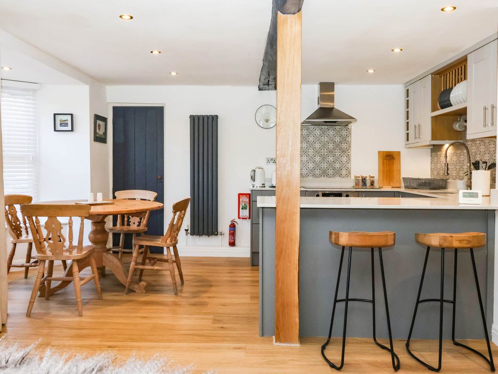 A kitchen with a table and bar stools at Winksey Cottage in Harrogate