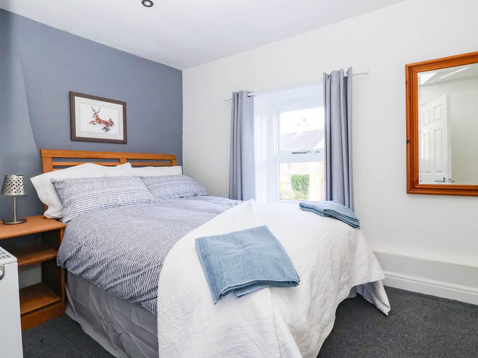 A bedroom with a bed and bedside table at Winksey Cottage in Harrogate