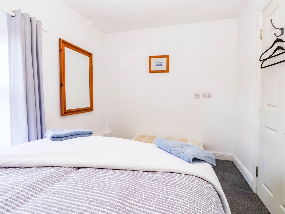 A bedroom with a bed, mirror, and towel at Winksey Cottage in Harrogate