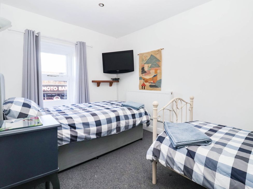 A bedroom with two beds and a television at Winksey Cottage in Harrogate