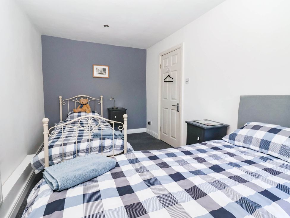 A bedroom with two beds and a desk at Winksey Cottage in Harrogate
