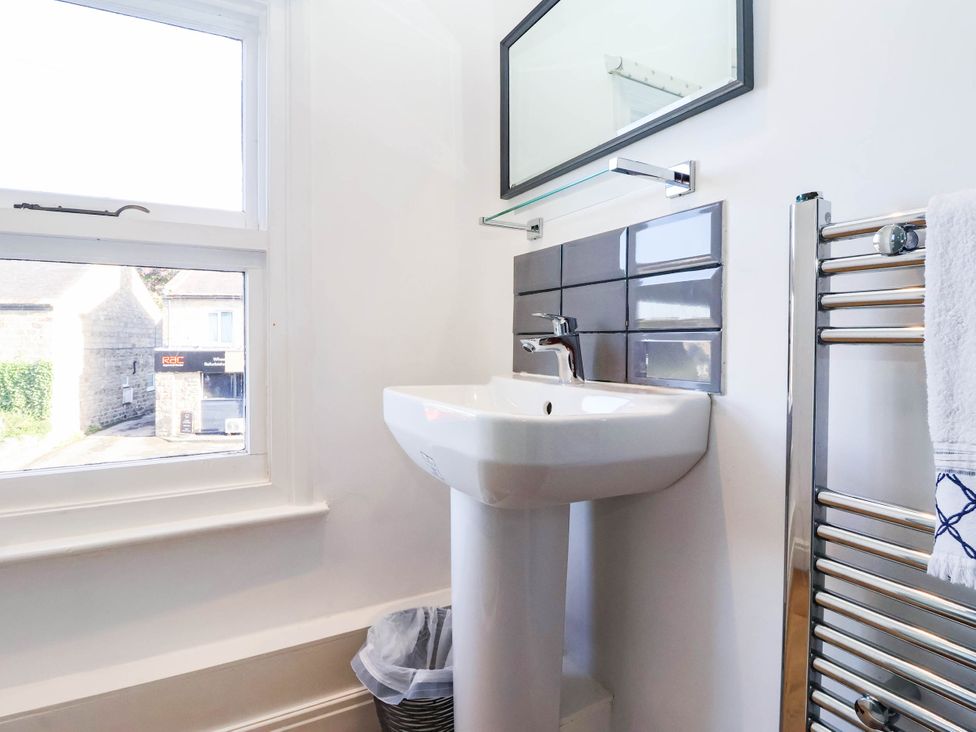 A bathroom with a wash basin and mirror at Winksey Cottage in Harrogate