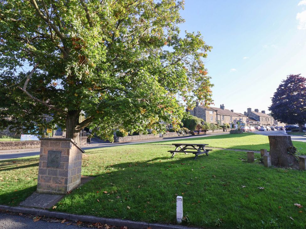 A green space with a tree and bench at Winksey Cottage Harrogate