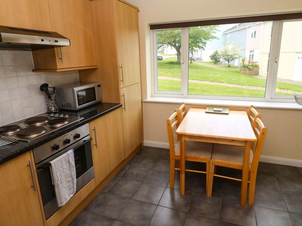 A kitchen with a stove, microwave, and dining table at 87 Atlantic Reach Newquay