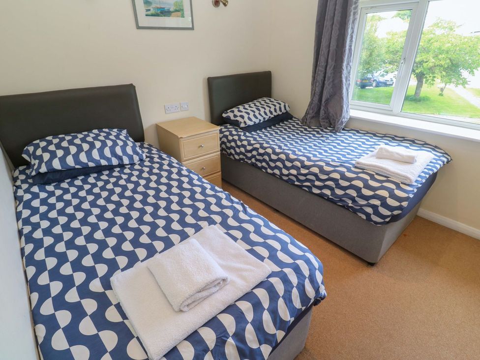 A bedroom with two single beds and a bedside table at 87 Atlantic Reach Newquay