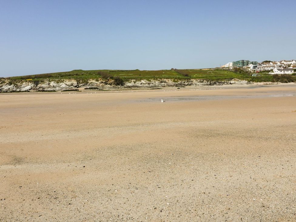 A beach with sand and a rocky cliff at 87 Atlantic Reach in Newquay
