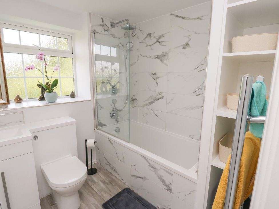 A bathroom with a bathtub, toilet, sink, and shelving at Nabwood views