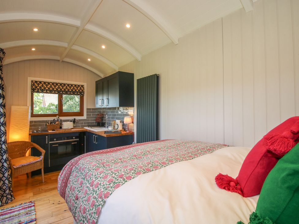 A bedroom with a kitchen area and a bed at Hideaway Hut at Hopton Court Estate near Cleobury Mortimer