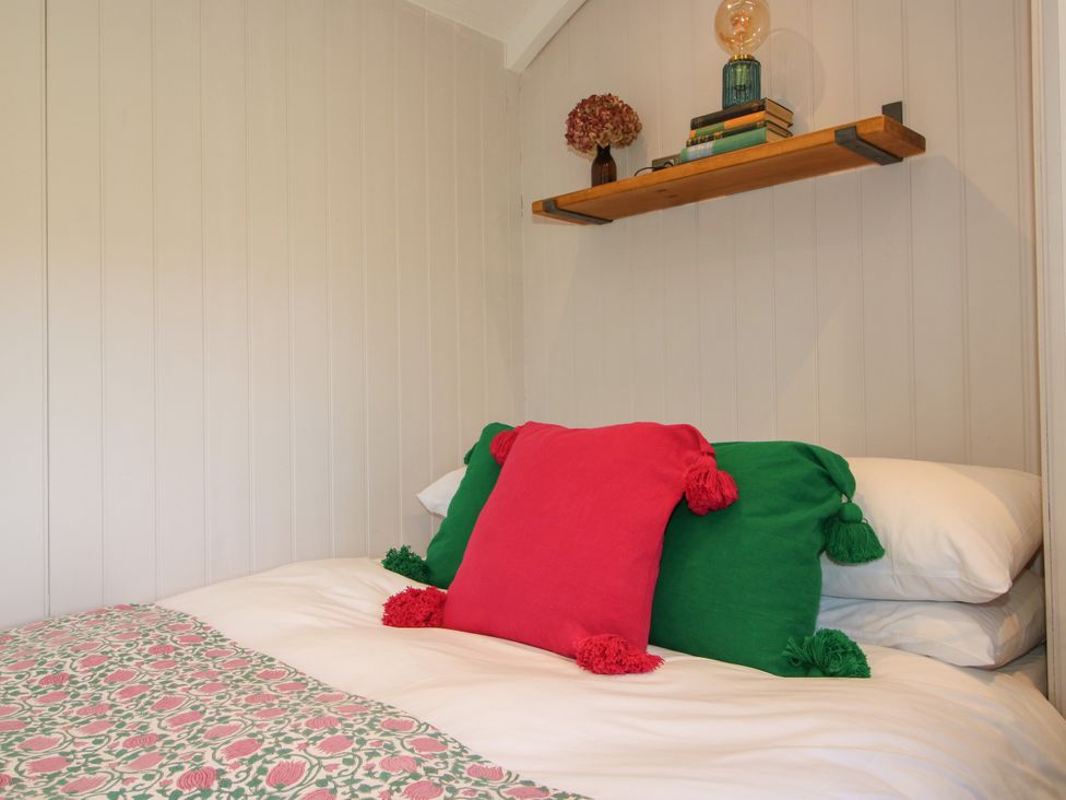 A bedroom with a bed and shelf at Hideaway Hut at Hopton Court Estate near Cleobury Mortimer
