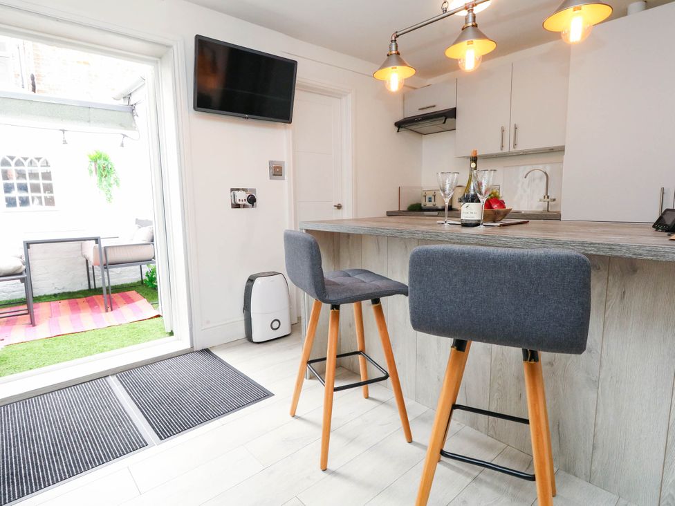 A kitchen with bar stools and a television at Flat 1, 2 Wooperton Street Weymouth