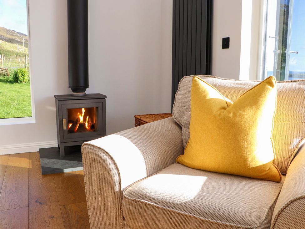 A living room with an armchair and wood stove at Holm Strond near Carminish Isle Of Harris