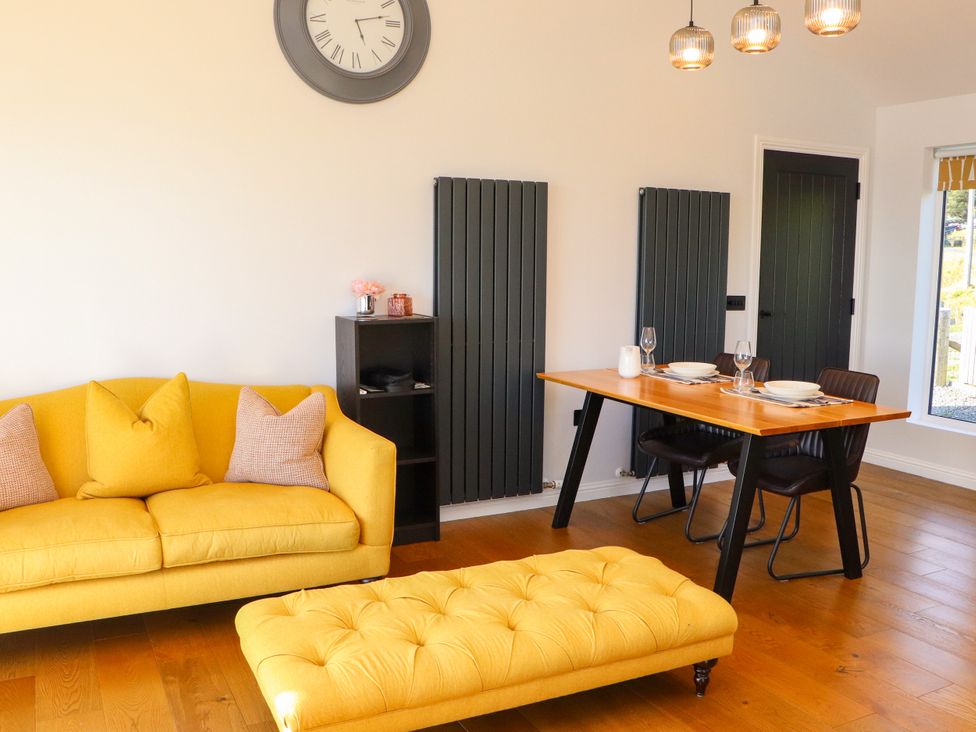 A living room with a yellow sofa and dining table at Holm in Strond near Carminish, Isle Of Harris
