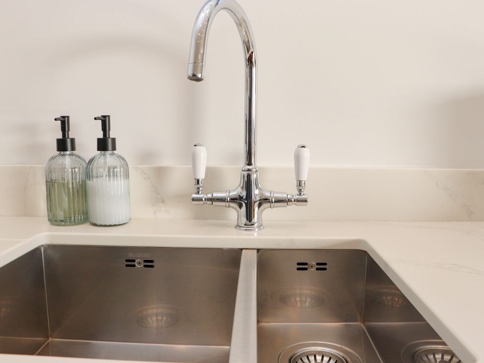 A kitchen sink with a faucet and soap dispensers at Holm in Strond near Carminish, Isle Of Harris