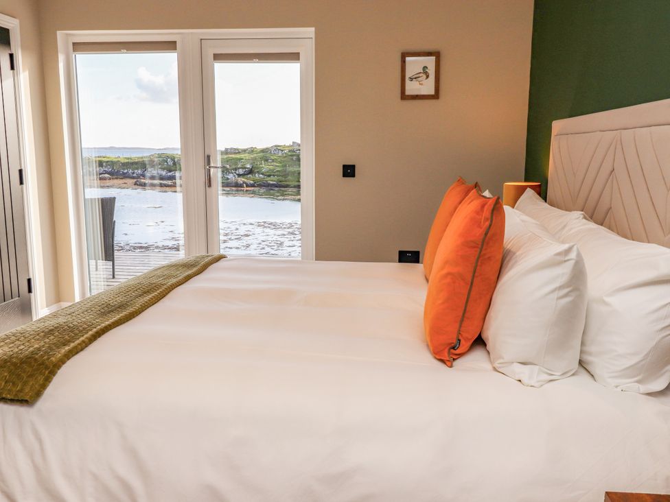 A bedroom with a bed and windows showing a view at Holm in Strond near Carminish, Isle Of Harris