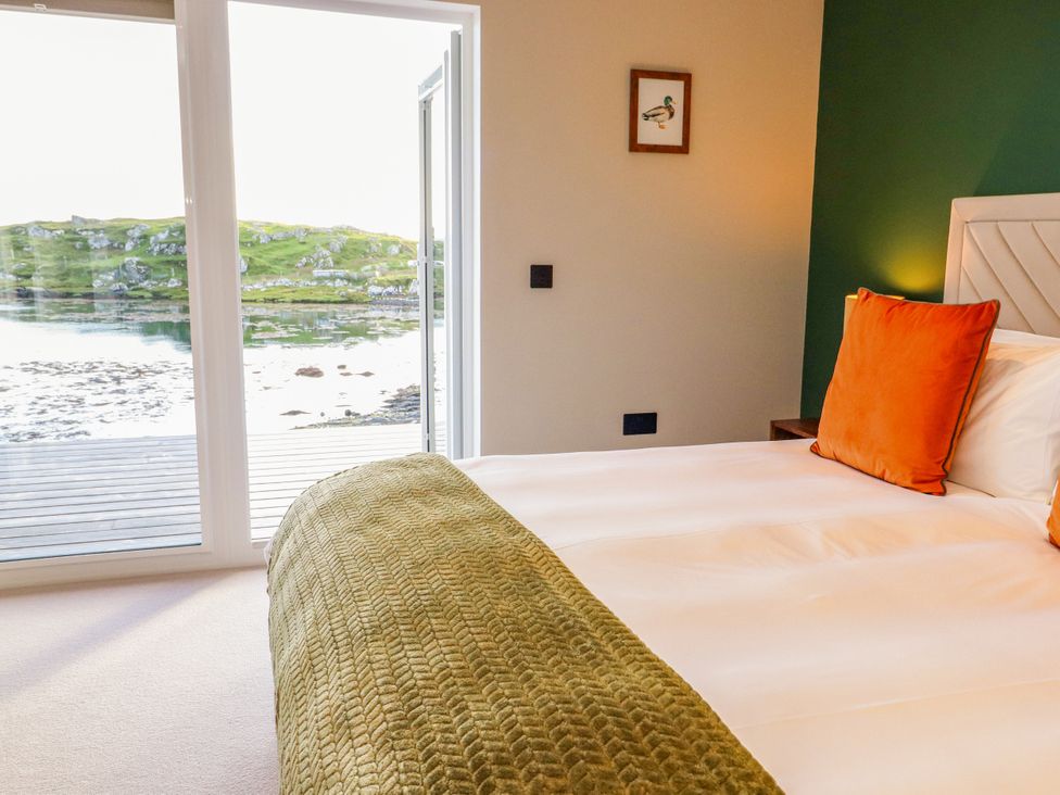 A bedroom with a bed and window overlooking a scenic view at Holm in Strond near Carminish, Isle Of Harris