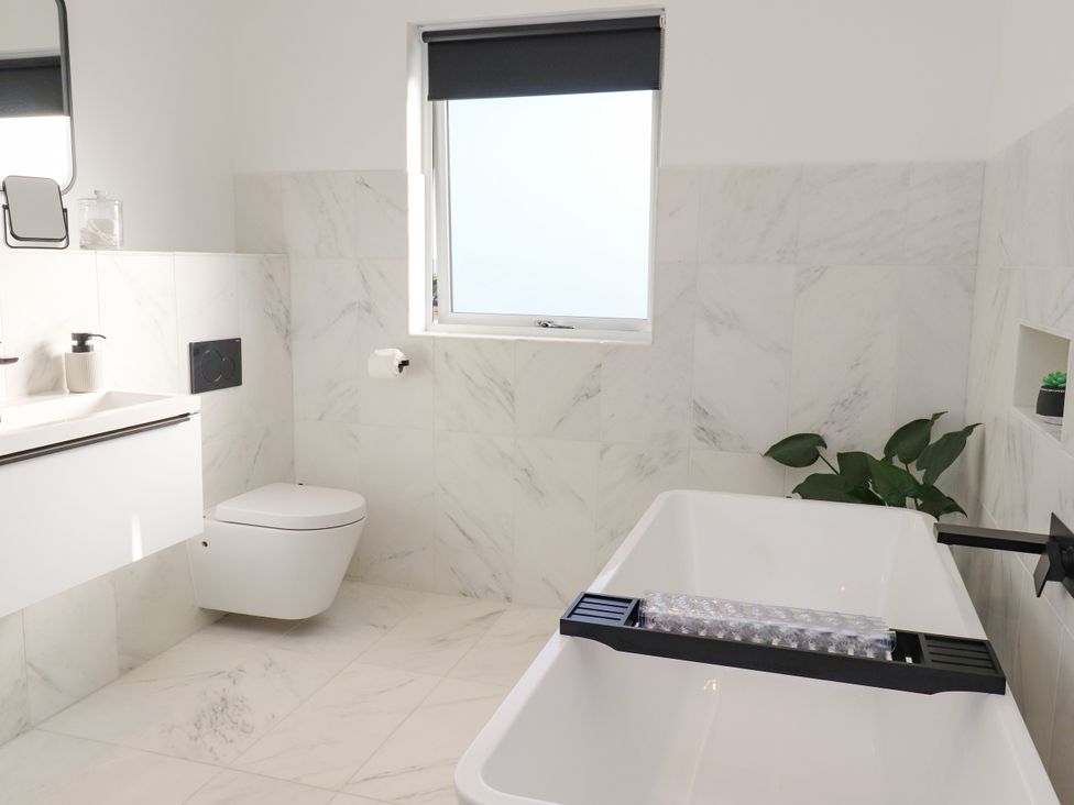 A bathroom with a bathtub, toilet, and sink at Holm, Strond near Carminish, Isle Of Harris