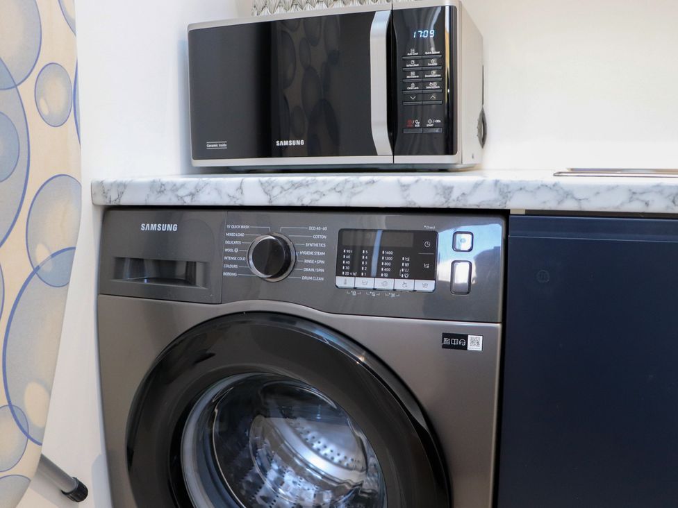 A washing machine and microwave on a countertop at Holm, Strond near Carminish, Isle Of Harris