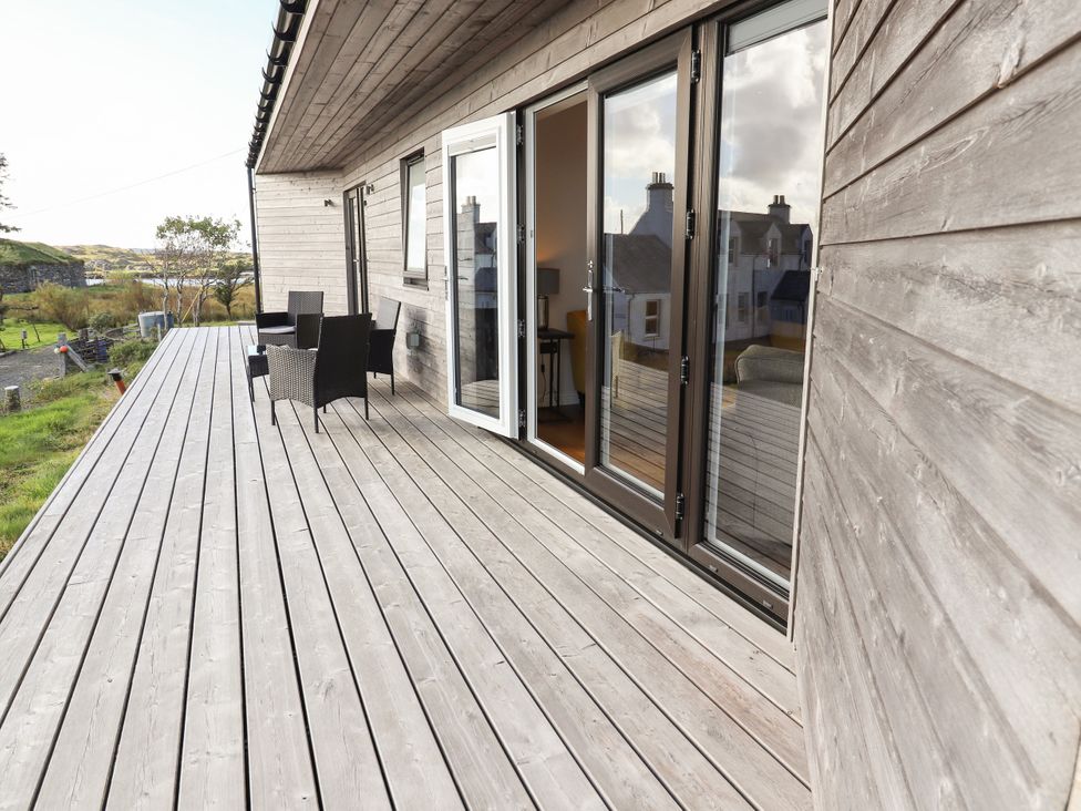 A deck area with furniture and sliding door at Holm in Strond near Carminish, Isle Of Harris
