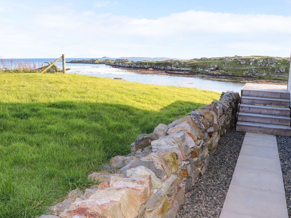 A garden with a stone wall and steps leading to water at Holm in Strond near Carminish, Isle Of Harris
