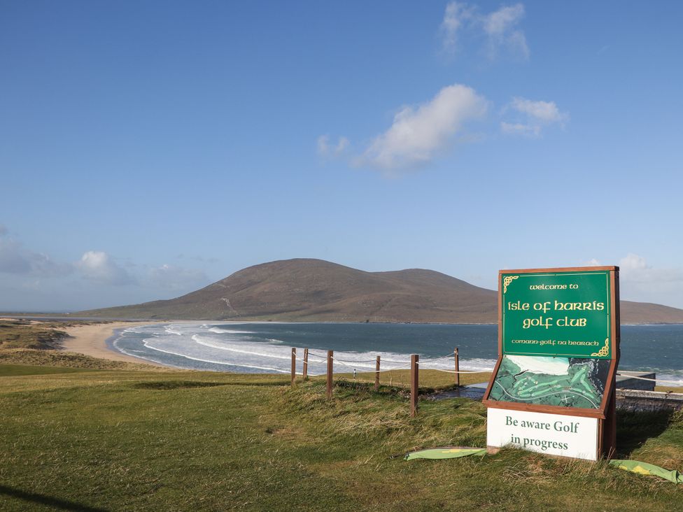 A golf club sign in front of a beach and hill at Isle of Harris in Leverburgh