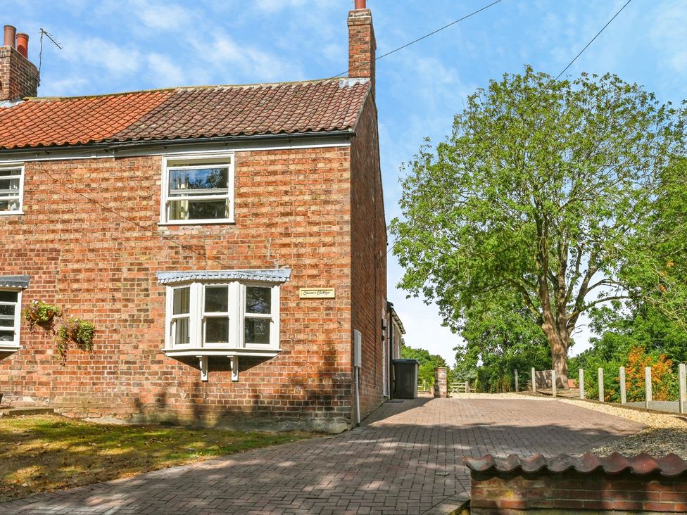 An exterior view of a brick cottage with a tree and pathway at Susans Cottage