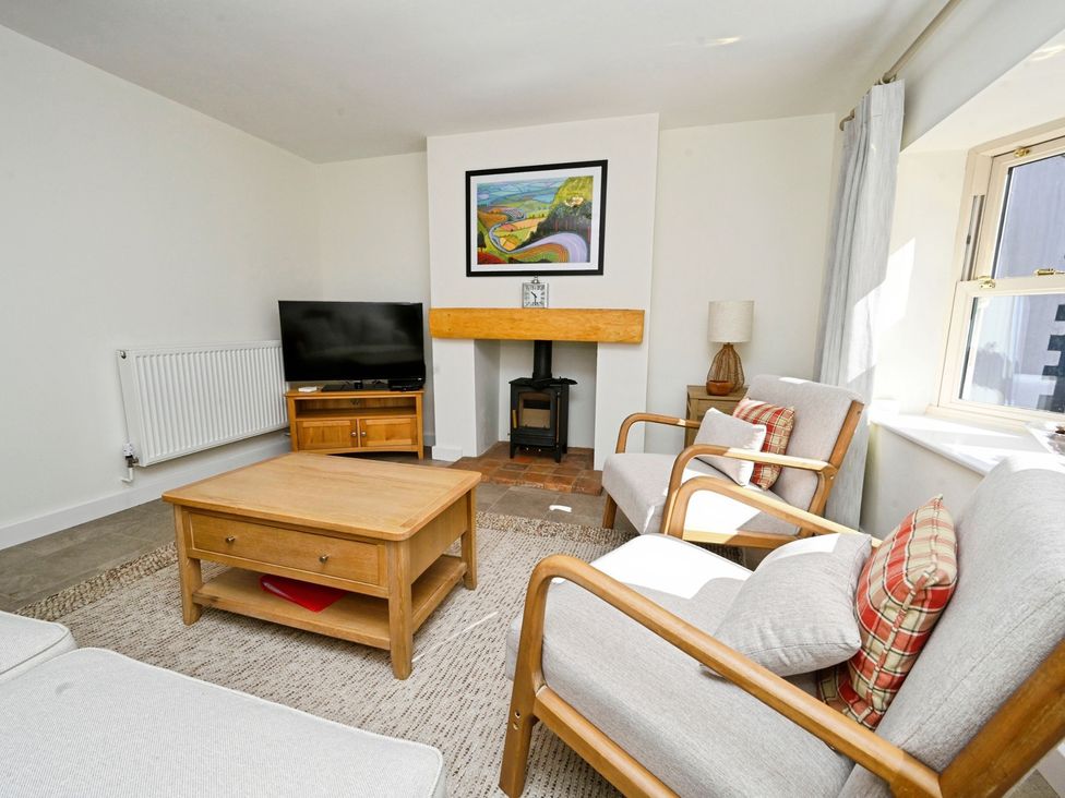 A living room with a sofa, armchair, coffee table, and television at Susans Cottage in 