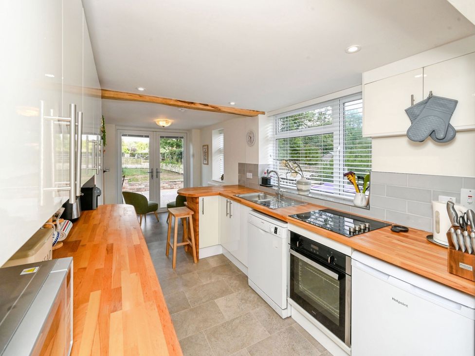 A kitchen with appliances and a bar stool at Susans Cottage