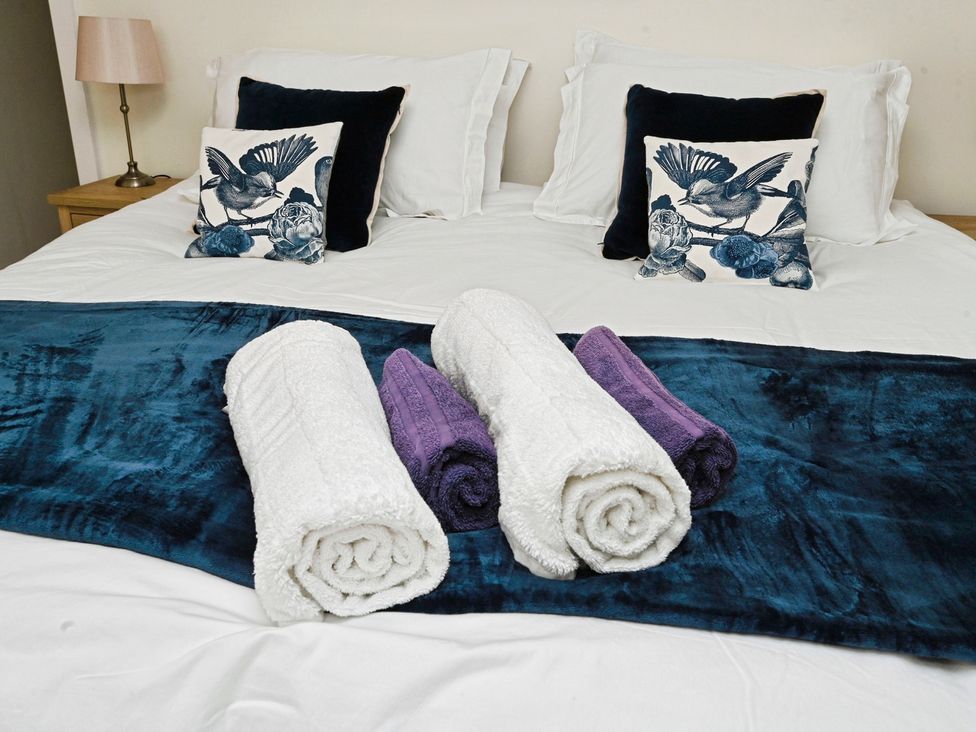 A bed with pillows and towels arranged on the bed at Susans Cottage