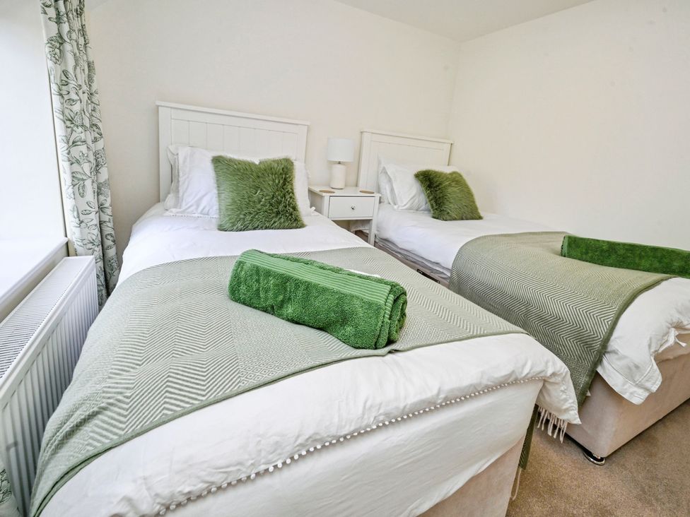 A bedroom with two single beds and a nightstand at Susans Cottage