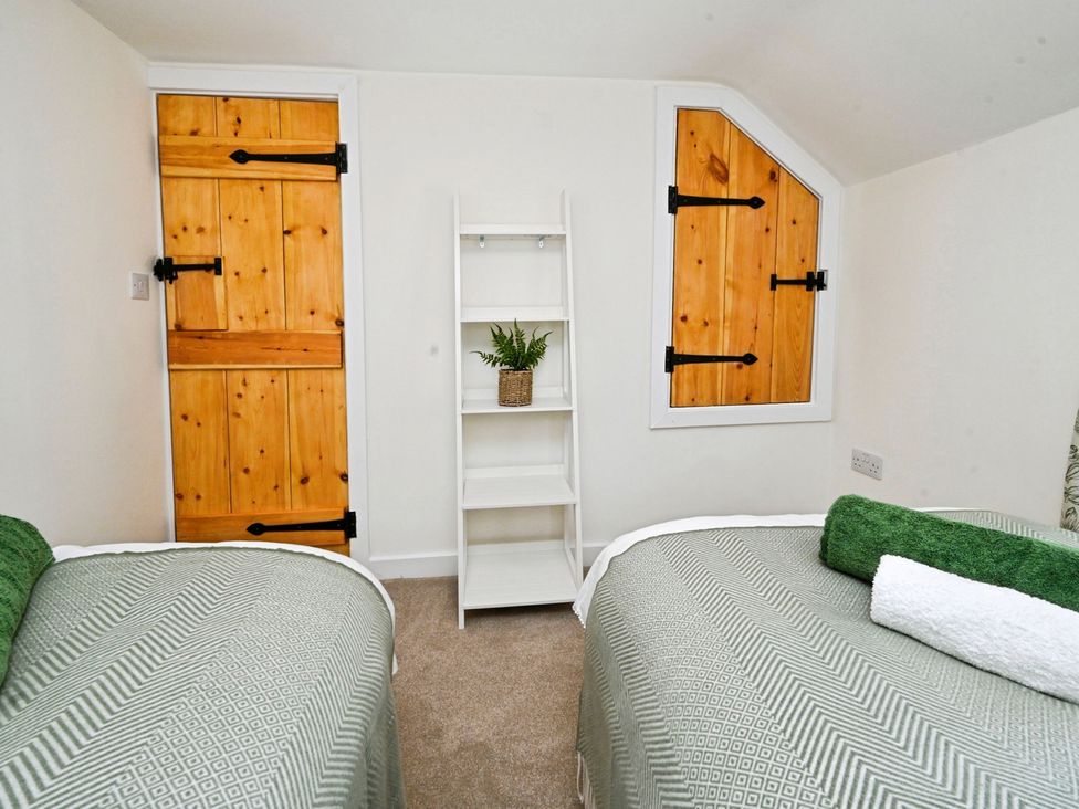 A bedroom with twin beds and wooden doors at Susans Cottage