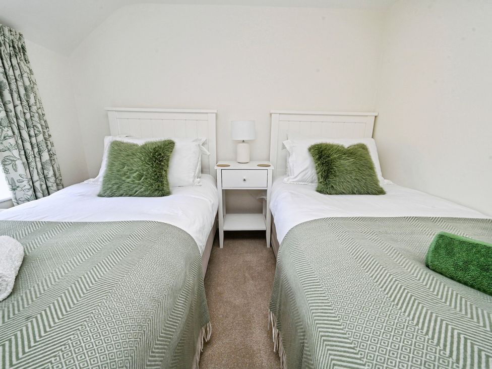 A bedroom with twin beds and a nightstand at Susans Cottage