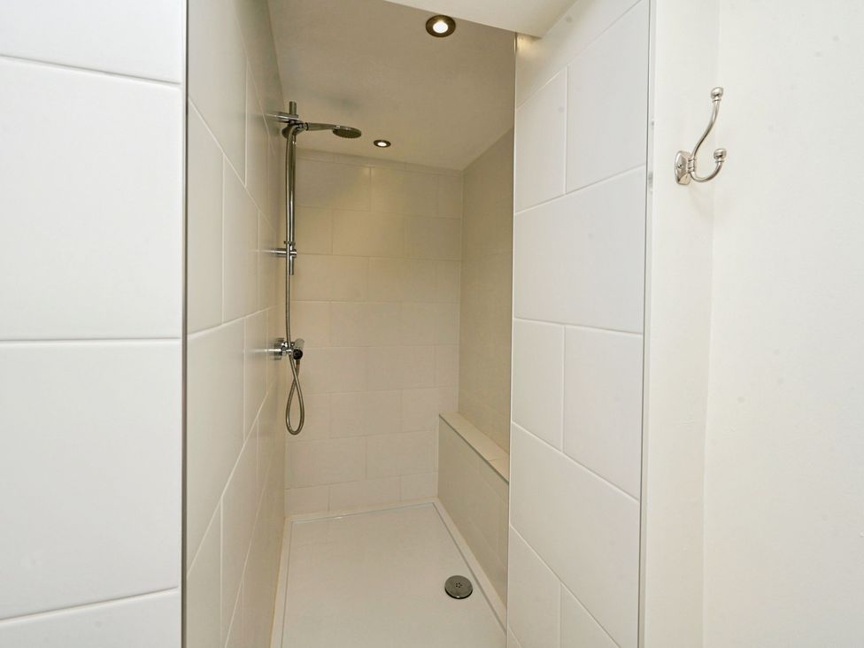A shower with a showerhead and wall tiles at Susans Cottage 