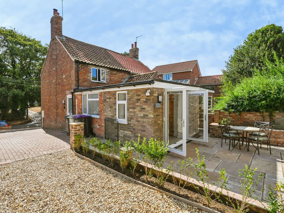 A garden with a table and chairs next to a brick house at Susans Cottage